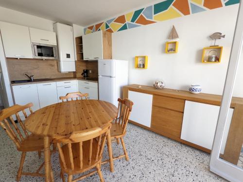 Il comprend une cuisine avec une table et des chaises en bois. dans l'établissement T2 Moderne Port-la-Nouvelle - 4/5p - Parking - Front de Mer - FR-1-797-41, à Port-la-Nouvelle