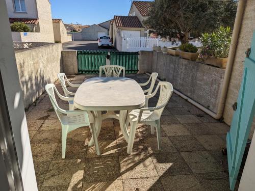 une table blanche et des chaises sur une terrasse dans l'établissement Villa T2 Mezzanine Climatisée avec Cour - 6 Pers - Parking - Proche Plage - Meublé Tourisme 1* - FR-1-797-44, à Port-la-Nouvelle