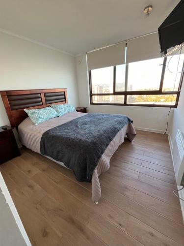 a bedroom with a bed and two large windows at Departamento JARDIN DEL MAR, 2 Dormitorios in Coquimbo