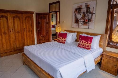 a bedroom with a large white bed with red pillows at Atres Griya Villa 5 Private Bedroom Kuta in Kuta