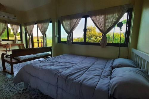 a bedroom with a large bed and a window at Naam and Nork Vegetarian Farmstay in Ban Rong Wua (2)