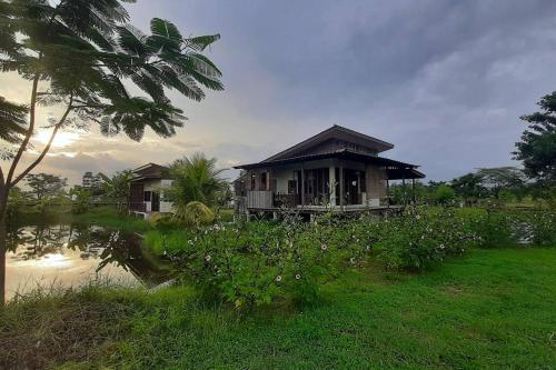 a small house in a field next to a body of water at Naam and Nork Vegetarian Farmstay in Ban Rong Wua (2)