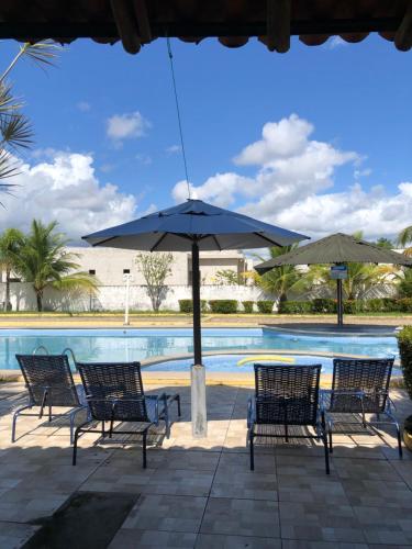 a group of chairs and an umbrella next to a swimming pool at Chalé em Barreirinhas - Porto dos Lençóis in Barreirinhas