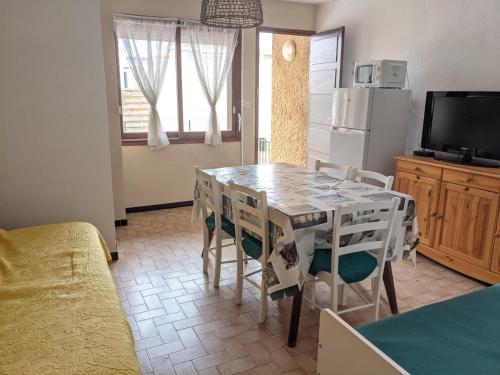 une cuisine avec une table, des chaises et un réfrigérateur dans l'établissement Villa T2 climatisée, 5 pers, proche plage, cour, jardin, barbecue, parking, 2* Meublés Tourisme - FR-1-797-57, à Port-la-Nouvelle