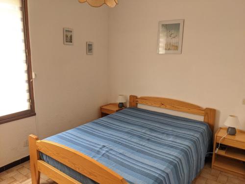 - une chambre avec un lit doté d'une couverture bleue dans l'établissement Villa T2 climatisée, 5 pers, proche plage, cour, jardin, barbecue, parking, 2* Meublés Tourisme - FR-1-797-57, à Port-la-Nouvelle