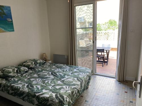 une chambre avec un lit et une porte coulissante en verre dans l'établissement Villa T2 cosy, 40m², 4 pers, proche plage, 2 terrasses, tout équipé, calme et commerces à proximité - FR-1-797-53, à Port-la-Nouvelle