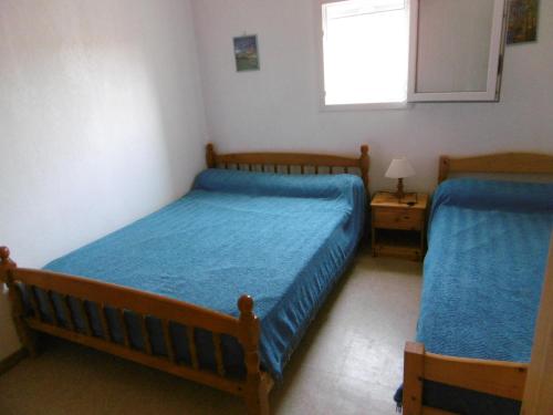 - une chambre avec 2 lits avec des draps bleus et une fenêtre dans l'établissement Maison T3 cosy avec terrasse et parking, proche plage - 6 pers, entièrement équipée, secteur calme - FR-1-797-54, à Port-la-Nouvelle