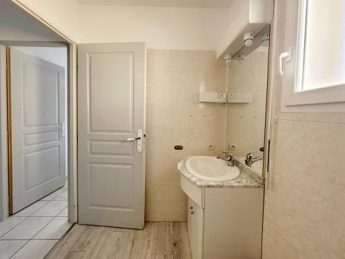 a bathroom with a sink and a white door at Canet en Roussillon - Maison T3 moderne pour 6 personnes - Terrasse spacieuse - Parking inclus - FR-1-794-147 in Canet-en-Roussillon