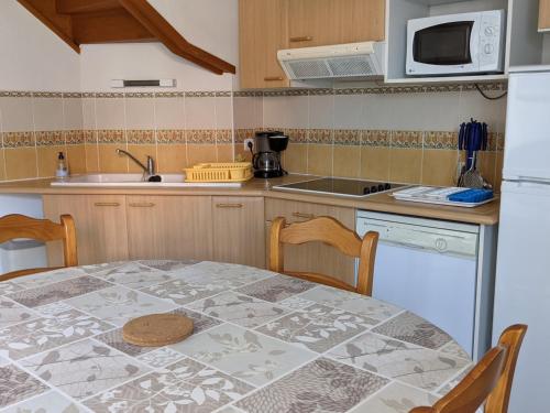 une cuisine avec une table et un réfrigérateur blanc dans l'établissement Maison T4 avec garage, clim, cour arborée, confort total – 6 Pers, à 200m de la plage - FR-1-797-55, à Port-la-Nouvelle