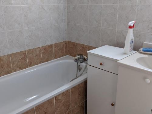 La salle de bains est pourvue d'une baignoire blanche à côté d'un lavabo. dans l'établissement Maison T4 avec garage, clim, cour arborée, confort total – 6 Pers, à 200m de la plage - FR-1-797-55, à Port-la-Nouvelle