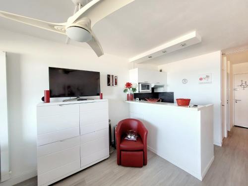une cuisine blanche avec une chaise rouge et un comptoir dans l'établissement Studio confort avec terrasse, vue mer et parking - Canet-en-Roussillon - FR-1-794-148, à Canet