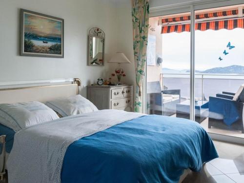 une chambre avec un lit bleu et un balcon dans l'établissement Beau 3 pièces au Lavandou avec terrasse et parking - FR-1-803-34, au Lavandou