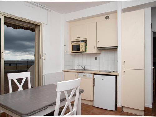une cuisine avec des armoires blanches et une table et des chaises dans l'établissement Studio cabine au Lavandou avec terrasse vue mer et parking privé, proche plage et commerces - FR-1-803-41, au Lavandou