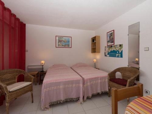 une chambre avec deux lits et deux chaises dans l'établissement Studio + cabine 4 pers avec parking et wifi au Lavandou - FR-1-803-49, au Lavandou