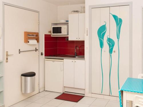 une cuisine avec des armoires blanches et une porte avec une fresque murale dans l'établissement Lavandou: Studio climatisé, terrasse, proche plage, 2 pers. - Pas d'animaux, sans parking - FR-1-803-43, au Lavandou