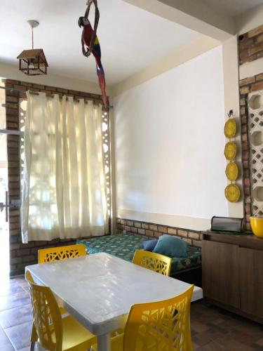 a dining room with a table and yellow chairs at Chalé em Barreirinhas - Porto dos Lençóis in Barreirinhas
