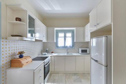 cocina blanca con armarios blancos y nevera en Aegean Villa in Paros, en Santa Marina