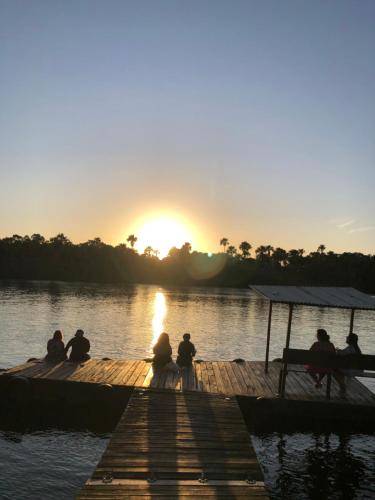 a group of people sitting on a dock at sunset at Chalé em Barreirinhas - Porto dos Lençóis in Barreirinhas