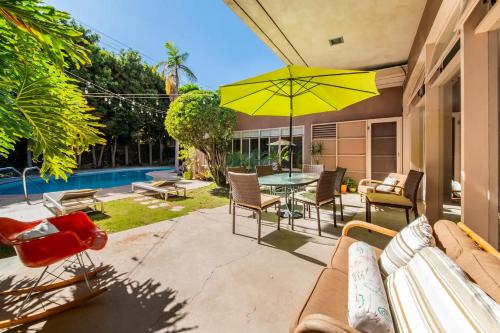 a patio with a table and chairs and a yellow umbrella at Bixby Beauty 50s Mod Long Beach in Long Beach