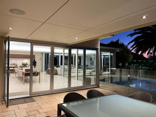 a house with glass doors and a patio with a table at Tanunda House - Luxury 5 BR in Barossa Wine Region in Tanunda