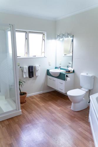 a white bathroom with a toilet and a sink at Pacific Coast Motor Lodge in Whakatane