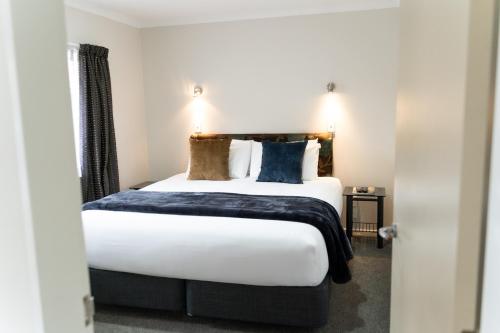a bedroom with a large bed with white sheets and pillows at Pacific Coast Motor Lodge in Whakatane