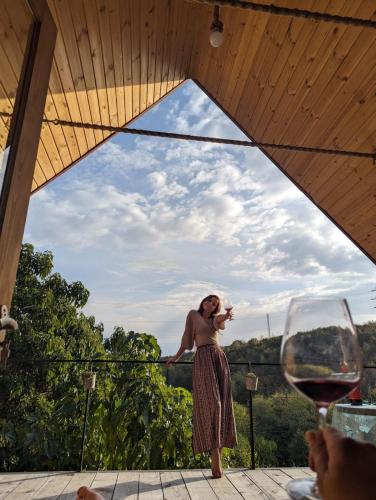 a woman standing on a balcony with a glass of wine at Cottage lima in Kutaisi