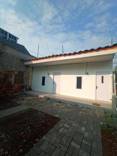 a large white house with a brick patio at ALMic INN BOGOR in Caringin