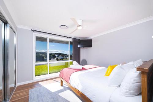 a bedroom with a bed and a large window at Magpie Rest in Forster