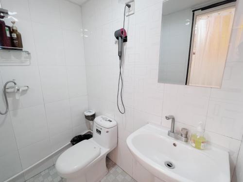 a white bathroom with a toilet and a sink at Mermaid's Secret-Bontique Homestay in Qingdao