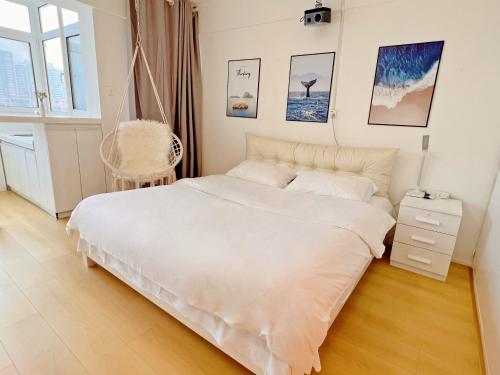a white bedroom with a bed and a chair at Mermaid's Secret-Bontique Homestay in Qingdao