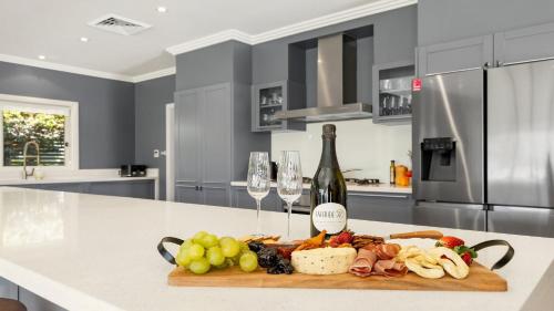 a cutting board with food and wine glasses on a kitchen counter at The Lake House - The Vintage in Pokolbin