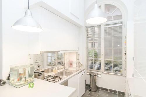 une cuisine blanche avec un évier et une cuisinière dans l'établissement Beautiful quiet family loft Paris, à Paris