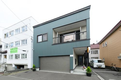 a blue building with a garage at Crea House in Sapporo
