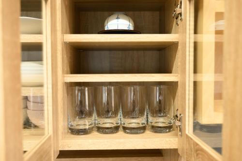 a cupboard with four empty glasses in it at Crea House in Sapporo