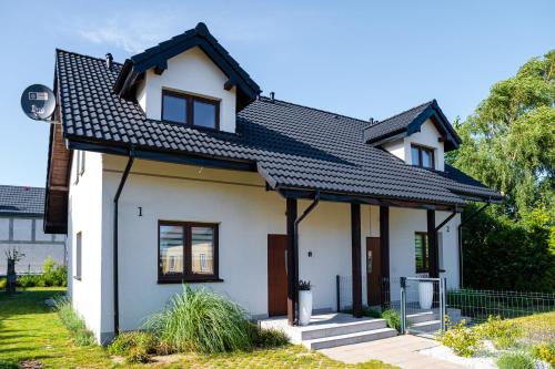 una casa blanca con techo negro en Morze Szczęścia, en Jastrzębia Góra