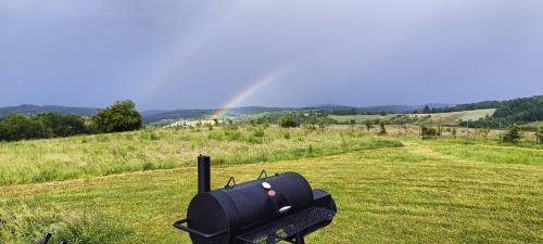 a black object in a field with a rainbow in the background at Mountaintop Panoramaview casa in Bihor apuseni in Vadul lui Carol II