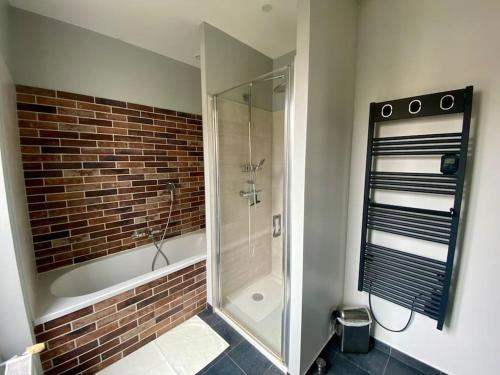 La salle de bains est pourvue d'une douche et d'un mur en briques. dans l'établissement Villa spacieuse 4 chambres proche Paris, à Clamart