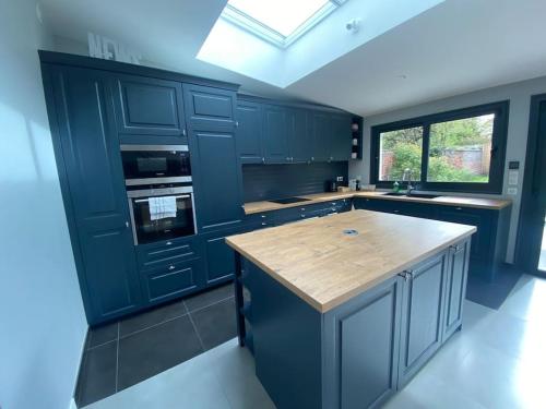 une cuisine avec des placards bleus et un comptoir en bois dans l'établissement Villa spacieuse 4 chambres proche Paris, à Clamart
