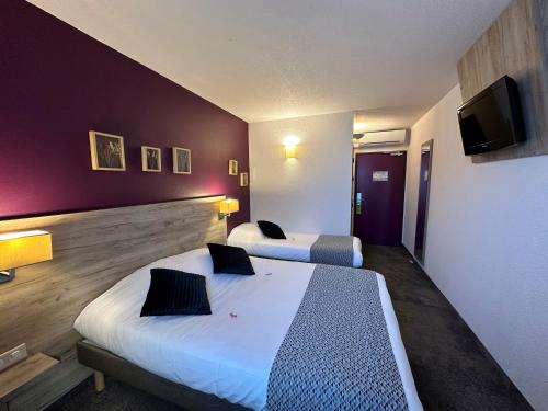 a hotel room with two beds and a flat screen tv at Brit Hotel Saumur in Distré