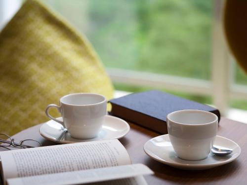 two coffee cups and a book on a table at Kinugawa Onsen Hotel in Nikko