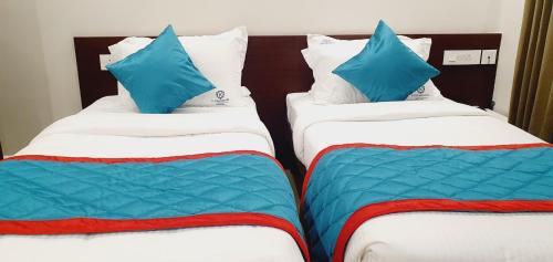 two beds in a hotel room with blue pillows on them at K Grandeur Hotels in Cochin