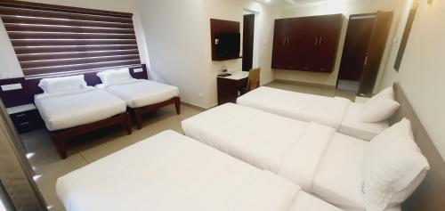 a hotel room with two beds and a couch at K Grandeur Hotels in Cochin