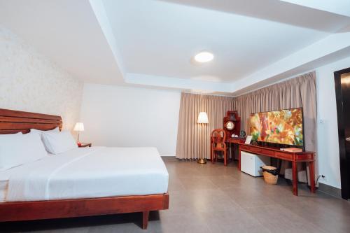 a bedroom with a bed and a desk with a television at Cambodian Country Club in Phnom Penh