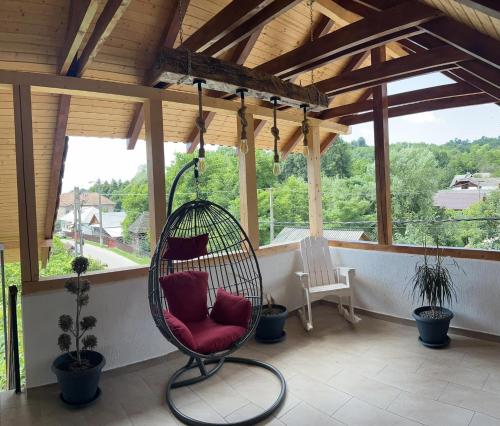 a porch with a chair in a swing at Pensiunea Valu in Bărbăteşti