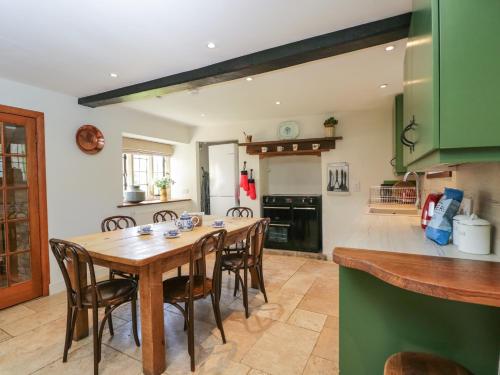 a kitchen and dining room with a wooden table and chairs at Rood Cottage in Burford