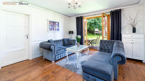 a living room with two blue couches and a table at Wonder Home - Domki górskie z kominkami na kameralnym osiedlu - plac zabaw na terenie kompleksu in Karpacz