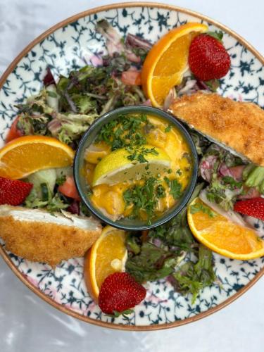 a plate of food with fruit and bread and a bowl at Hotel Luther Birke Wittenberg in Lutherstadt Wittenberg