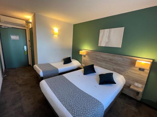 two beds in a hotel room with green walls at Brit Hotel Saumur in Distré