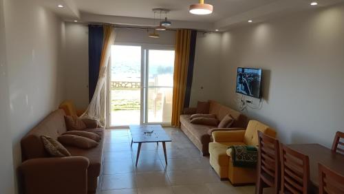 a living room with couches and a table and a window at شاليه Do1 ثلاث غرف مكيف بالكامل 2حمام للايجار بمطروح قرية لونج ايلند كورنيش روميل "family" in Marsa Matruh